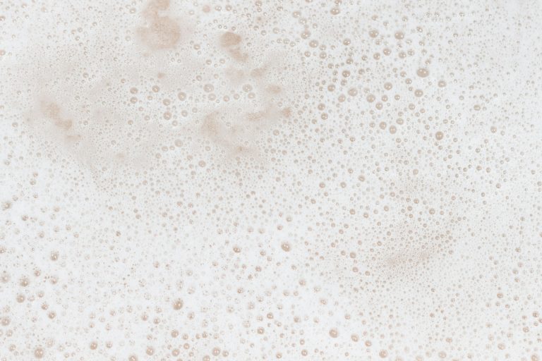 Gros plan d’une mousse onctueuse aux fines bulles, dans des tons crème