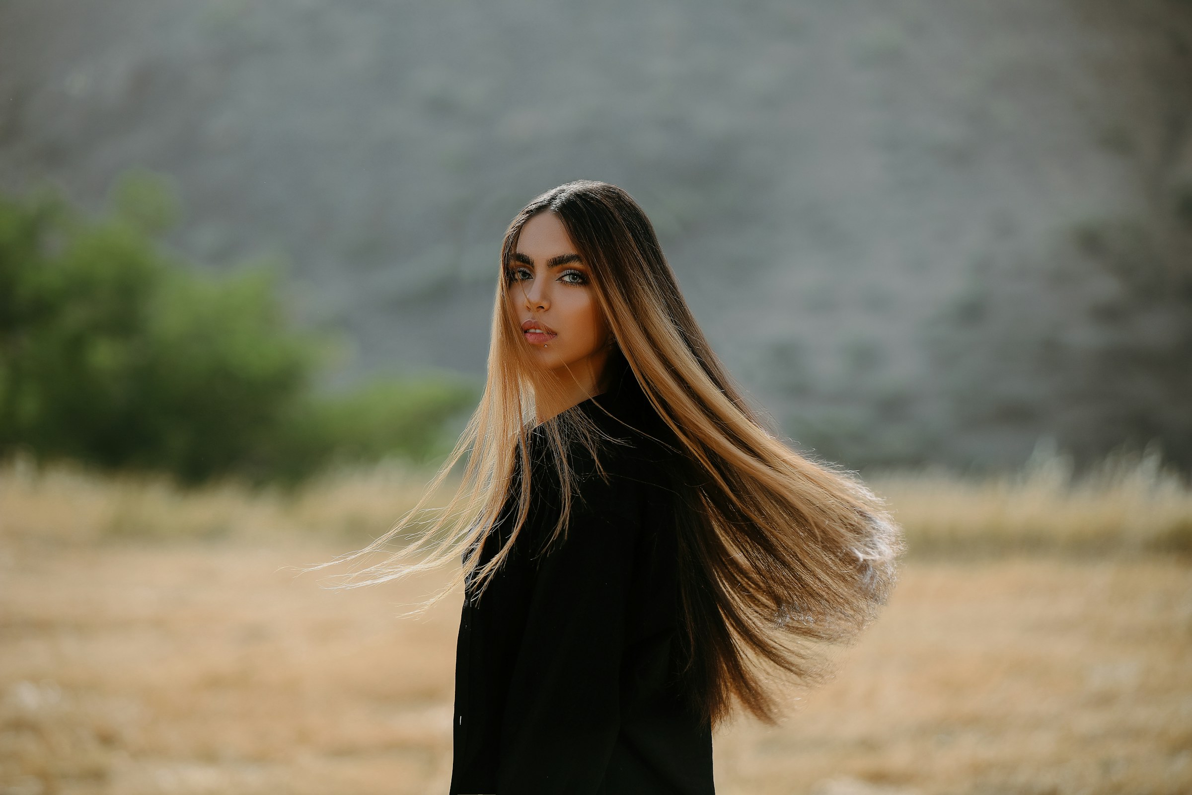 Femme aux longs cheveux lisses et brillants en mouvement, dans un paysage aux tons dorés