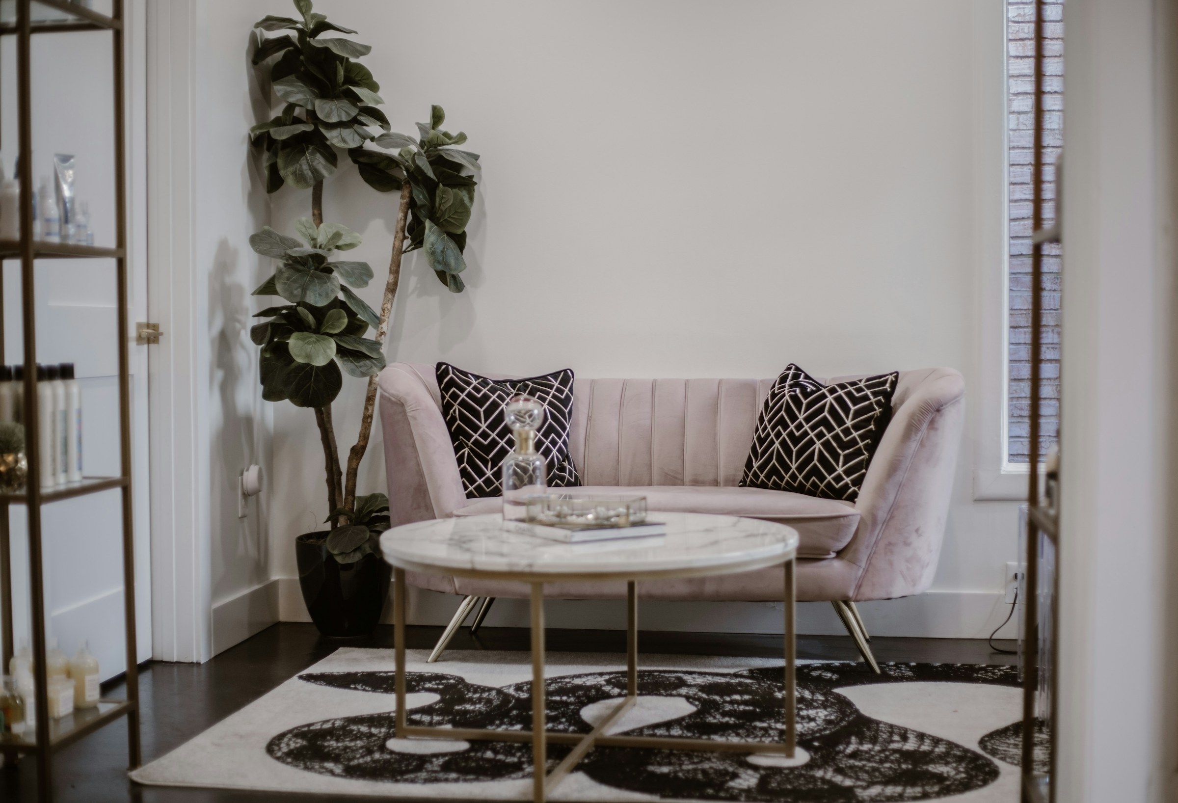 Espace d’accueil lumineux avec canapé rose poudré, table basse en marbre et plante verte
